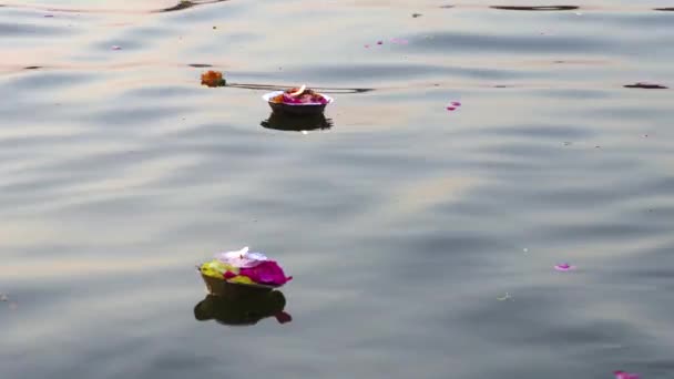 ヒンドゥー教の宗教的な儀式供養花、バラナシ、インド、クローズ アップ、4 k 映像ビデオで聖なる川ガンジス川水のロウソク — ストック動画