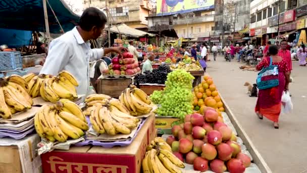 India, Varanasi, India, Mar 10, 2019 - Vendedores que venden frutas frescas, plátano, manzanas, uvas en el viejo mercado en Varanasi, India, video de imágenes 4k — Vídeos de Stock