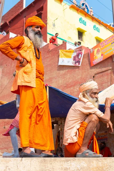 VARANASI, INDIA, MAR 10 2019 - Dos hombres santos hindúes no identificados, de pie sobre el ghat cerca del río Ganges en Varanasi, India — Foto de Stock