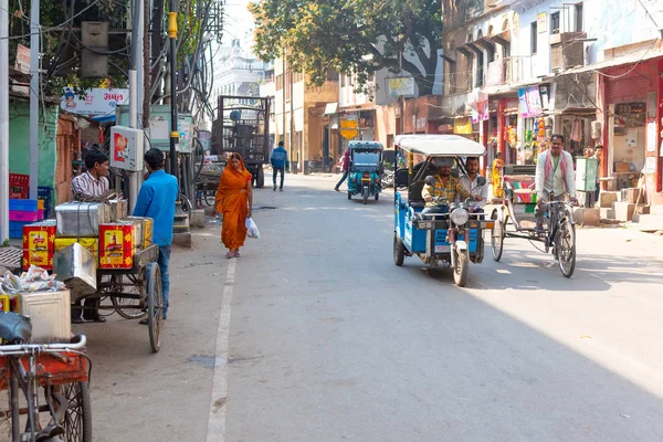 VARANASI, INDIA, 10 MAR 2019 - Movimiento de personas con los ciclos y vehículos tuk-tuk en la calle Varanasi — Foto de Stock