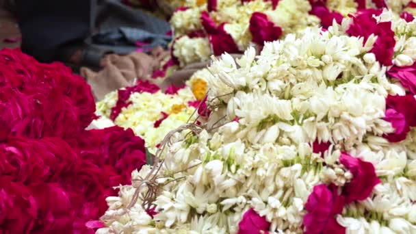 Uomo indiano che sorregge ghirlande di fiori dai colori vivaci in un mercato di fiori vicino al fiume Ganga, Varanasi, India, 4k filmati video — Video Stock