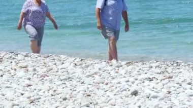 Beyaz kum taşlı plajda berrak Akdeniz'e yakın yürüyen Orta Çağ Çift
