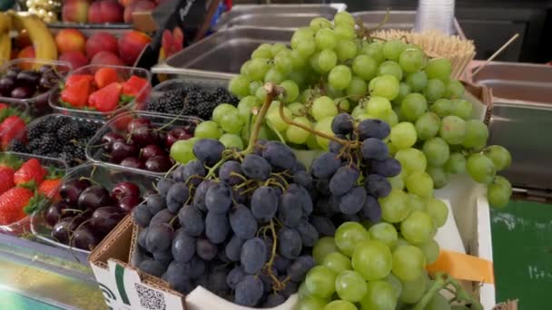 Mélange de baies dans des boîtes en plastique sur le marché prêt à la vente. bleuets, figue, mûres, fraises, raisin — Video