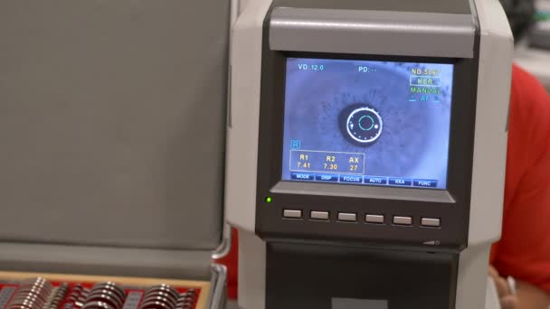 Patientin Nahaufnahme Auge auf eine Augenuntersuchung modernen Autorefraktor computergesteuerte Maschine. Arztbesuch in der Augenklinik mit Brille im Hintergrund — Stockvideo