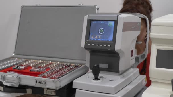Vrouwelijke patiënt close-up oog op een oogonderzoek moderne autorefractor computergestuurde machine. Medische aanwezigheid in de optometrie kliniek met glazen op de achtergrond — Stockvideo