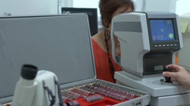 Orta yaşlı kadınların göz muayenesi modern otomatik fraktör bilgisayar kontrollü makine. Optometri kliniğinde arka planda gözlüklerle tıbbi katılım