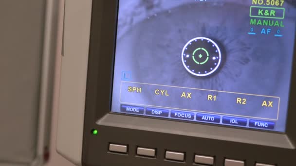 Female patient closeup eye on a eye examination modern autorefractor computer-controlled machine. Medical attendance at the optometry clinic with glasses in background — Stock Video