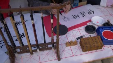 Geleneksel Japon kaligrafisini yazmak için büyük bir mürekkep fırçası ve pul kullanarak yavaş çekim, elin yakın çekim çekimi