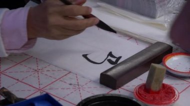 Yavaş çekim, geleneksel Japon kaligrafisini yazmak için büyük bir mürekkep fırçası kullanarak elin yakın çekim çekimi