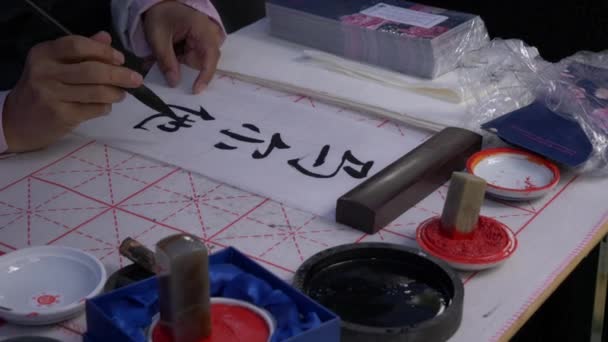 スローモーション、大きなインクブラシを使って伝統的な日本の書道を書く手のクローズアップショット — ストック動画