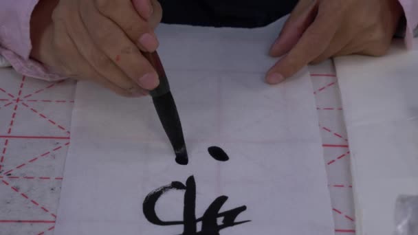 Yavaş çekim, geleneksel Japon kaligrafisini yazmak için büyük bir mürekkep fırçası kullanarak elin yakın çekim çekimi — Stok video