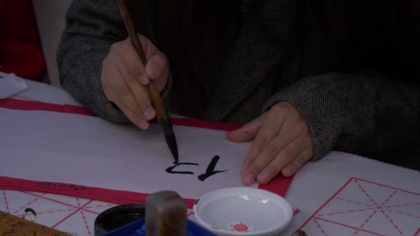 Slow motion, close-up shot of hand using a large ink brush to write traditional Japanese calligraphy — Stock Video