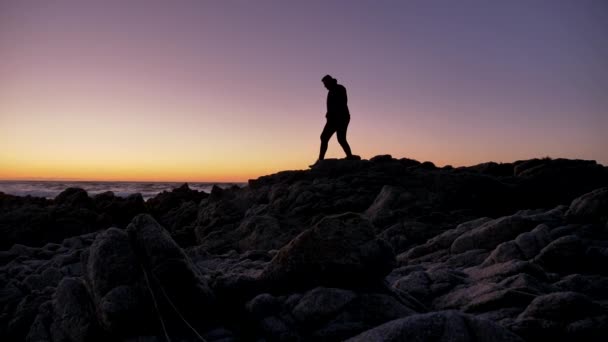 男は海の海岸の岩の上でリラクゼーション技術を練習 — ストック動画