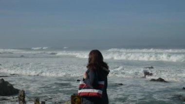 Okyanus yolunda yürüyen yaşlı kadın kapalı sörf tabelası sarılma dalgaları.