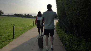 Birkaç mutlu insan valizlerle yürüyor. Laguna Beach California 'da telefonla konuşuyorlar.