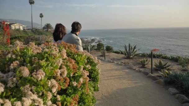 Coppia sulla panchina a Laguna Beach splendida vista con bellissimi fiori — Video Stock