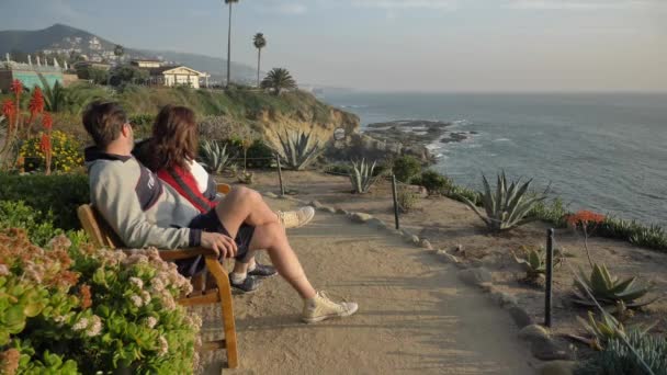 Casal no banco de Laguna Beach vista incrível. EUA California Laguna beach Janeiro 2020 — Vídeo de Stock