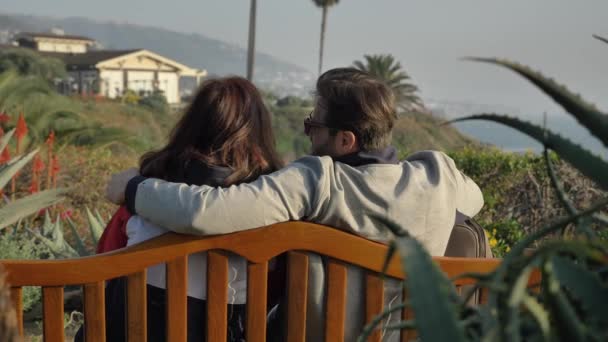 Para na ławce mężczyzn całujących kobietę w Laguna Beach niesamowity widok — Wideo stockowe