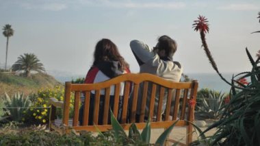 Mutlu çift Laguna Sahili 'nde bankta oturuyor. Manzaraya bayılıyor.