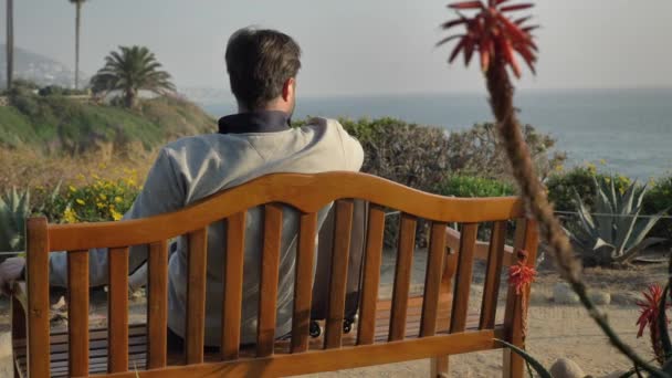 Gli uomini si siedono sulla panchina a Laguna Beach ammira la vista panoramica magnifica vista — Video Stock