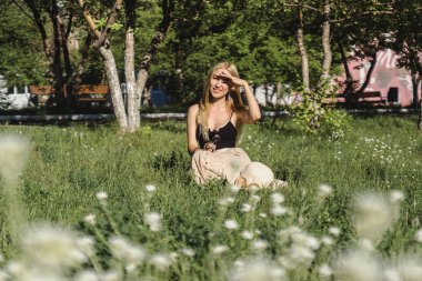 Kız çimenlerin üzerine parlak güneşli bir günde oturuyor.