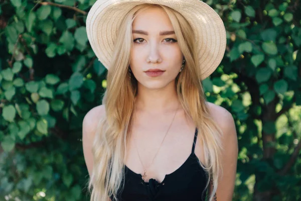 Dívka v klobouku na pozadí zelené listí — Stock fotografie