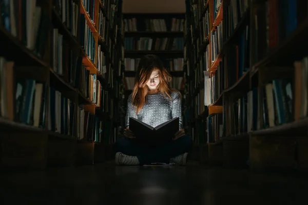 Une fille lisant un bookin à la bibliothèque publique assise par terre. La fille dans la bibliothèque publique — Photo