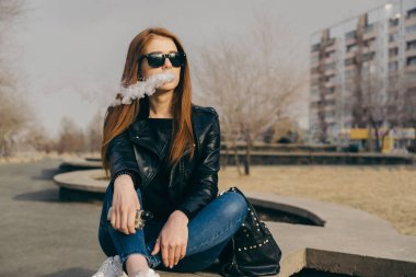 Güneş gözlüklü kız Buhar ağzından dışarı sağlar. Kızıl saçlı vape kız.