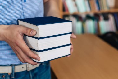Erkek eller bir yığın kitap tutuyor..