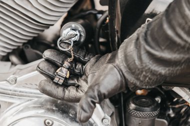 Bratsk, Rusya - 26 Nisan 2019: Deri ceketli ve deri eldivenli bir motorcu kontak anahtarı için bir anahtarlık tutuyor..