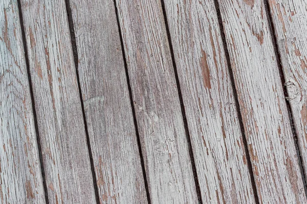 A whitewashed wooden surface worn out due to weather. Planks painted white. The texture of the wooden board.