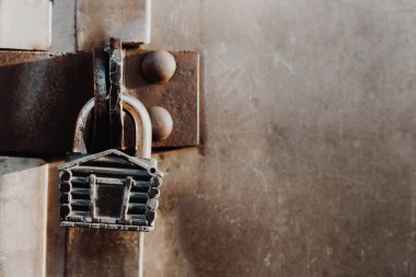 Kulübe şeklinde asma kilit kapalı kapının menteşelerinde asılı duruyor. Metal kapılar.