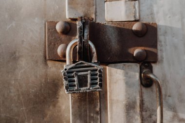 Kulübe şeklinde asma kilit kapalı kapının menteşelerinde asılı duruyor. Metal kapılar.