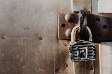 Kulübe şeklinde asma kilit kapalı kapının menteşelerinde asılı duruyor. Metal kapılar.