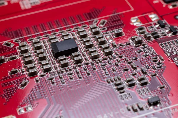 Transistors from the back of the video card under the graphic core. Macro shooting of a red microcircuit. The concept of a microscopic city.