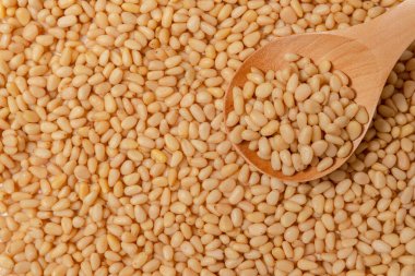 Soyulmuş çam fıstığı. Kabuksuz çekirdekler. Tahta kaşıkta fındıklar yatıyor.