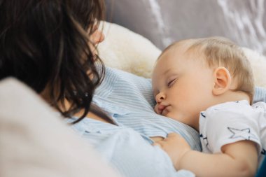 Küçük bebek annesinin göğsünde uyuyor.