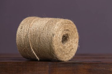 Büyük bir kahverengi sicim, düz bir arka planda, ahşap bir rafta yatar.