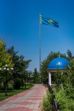 Çardağı ve sokak lambasıyla parkta Kazakistan bayrağı sallıyor..