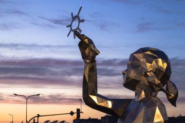 gün batımının arka planına güneşçizen bir kız heykeli, Poznan. Polonya