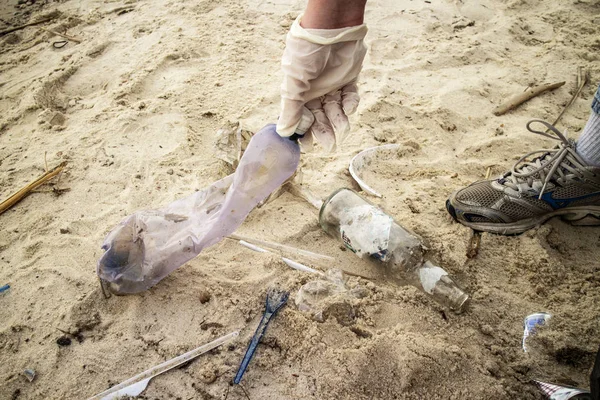 Genç bir kadın, Kiev Denizi kıyısındaki sert plastik şişeler ve diğer çöplerle dolu kumlu sahilde bir çöp torbasında plastik çöp topluyor. (Gönüllü konsept)
