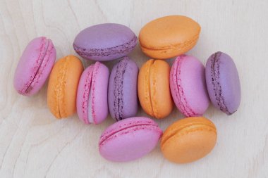 ahşap arka plan üzerinde birçok renkli macaroons için tasarımcı bir düzenleme olarak boş bir içine katlanır