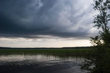 gün batımında sazlık ve bulut yansımaları ile göl manzara. Yağmurdan önce fırtına bulutları.