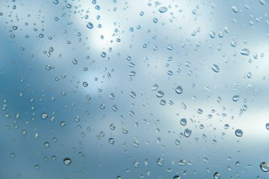 Bulutlar yakın açık gökyüzü arka plan üzerinde cam üzerinde Raindrops 