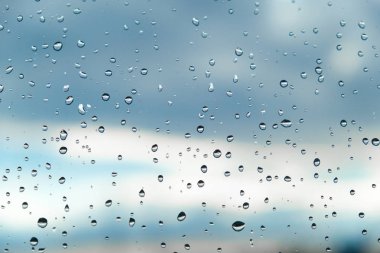 Gökyüzüne karşı şeffaf bir pencere üzerinde Yağmur damlaları ve bulutlar clo