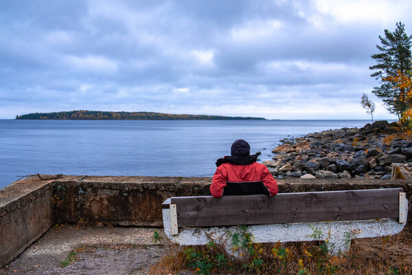 oung парень в теплой куртке и шляпа сидит на скамейке перед
 