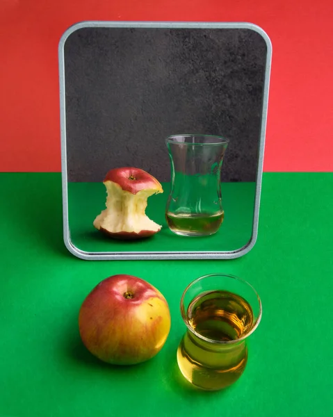 The concept of an Apple and the juice in the reflection. Half empty, half full. Abstraction, art.