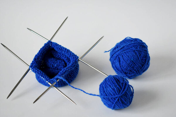 Кусок вязания с клубком пряжи и вязальными спицами
