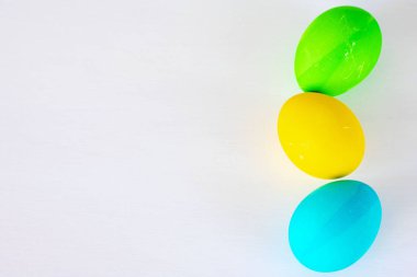 Paskalya yumurtaları beyaz arka planda izole renkli. Minimal Paskalya konsepti. Metin için kopya alanı ile mutlu paskalya kartı. Üst görünüm, düz.