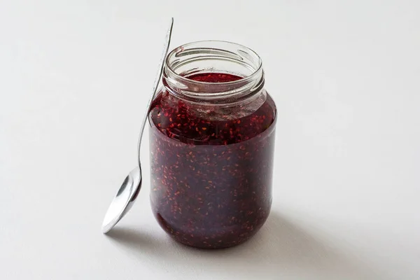 Botol kaca dengan selai merah di atas meja — Stok Foto